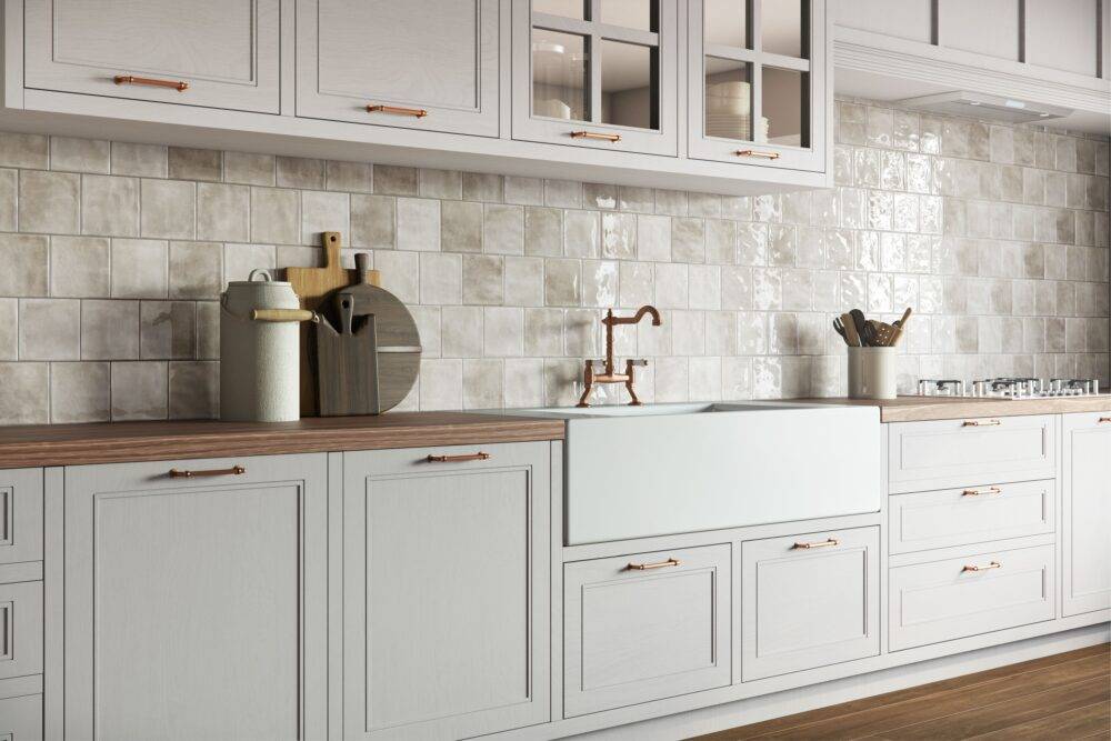 Kitchen with white cabinets and square white and beige handmade-look tile. 