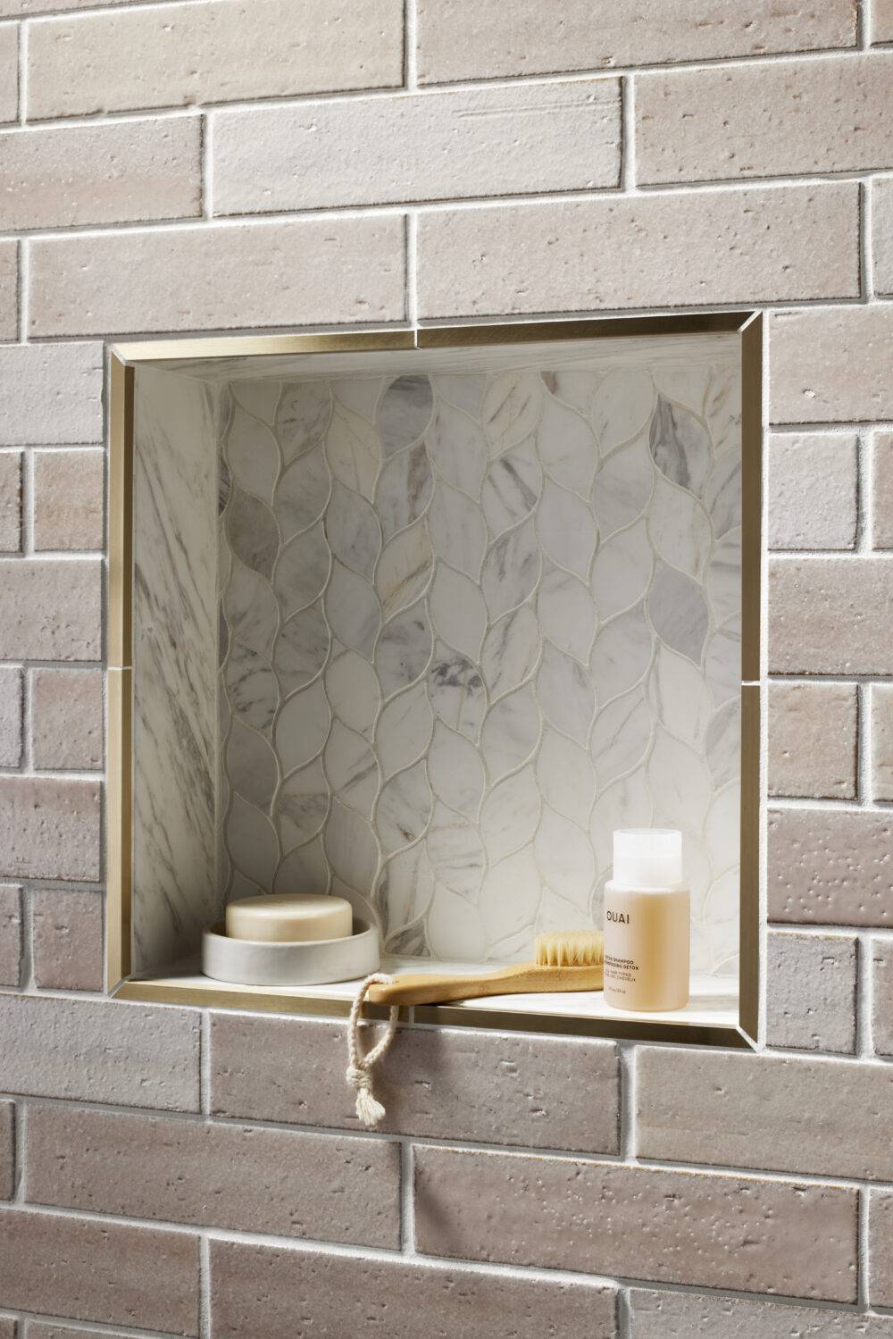 Pink brick-look tile with mosaic leaf-shaped tile shower niche. 