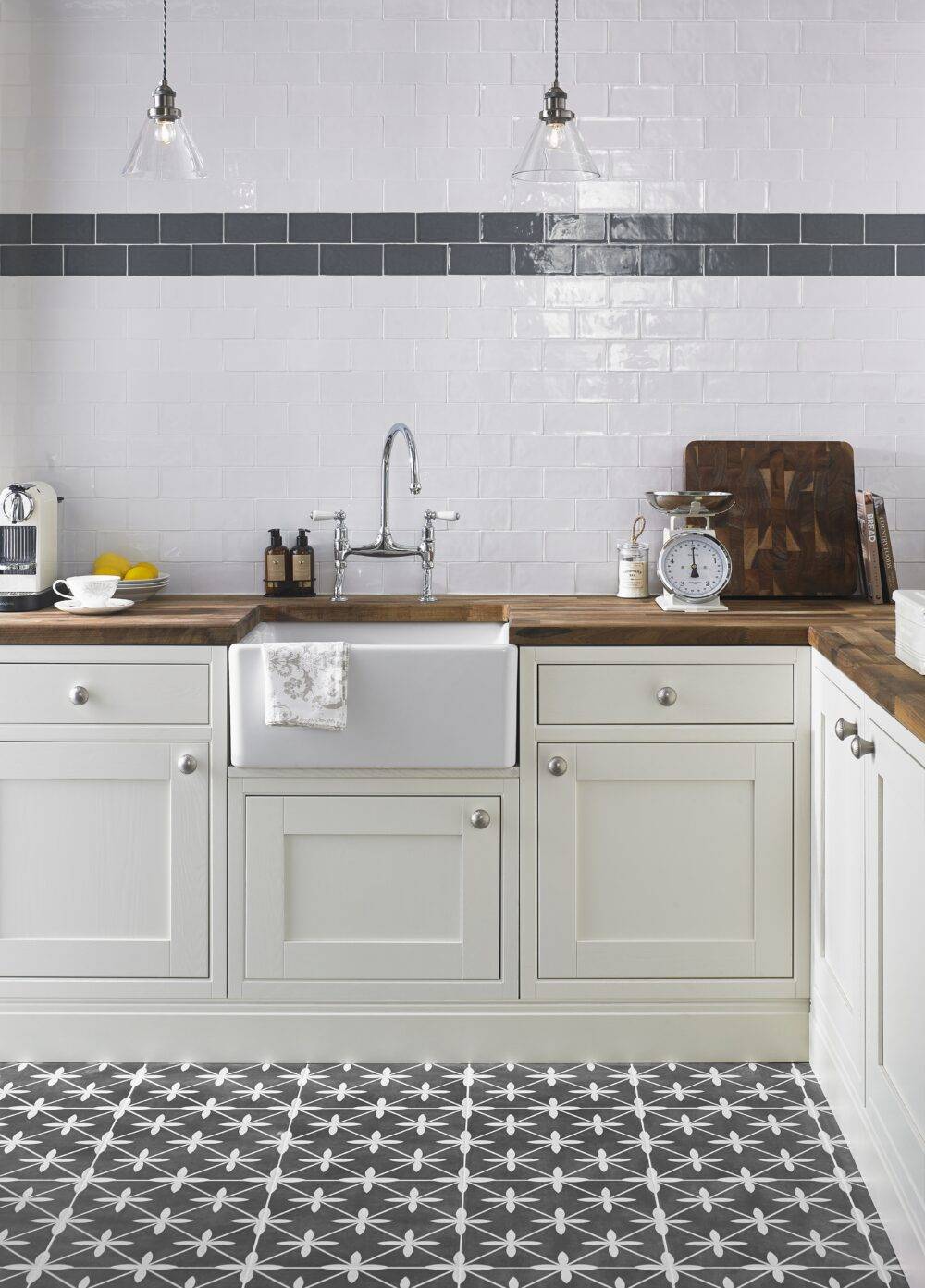 Kitchen area with white subway tile and a blue  border also in this collection.  The floor is a patterned ceramic in charcoal and white.