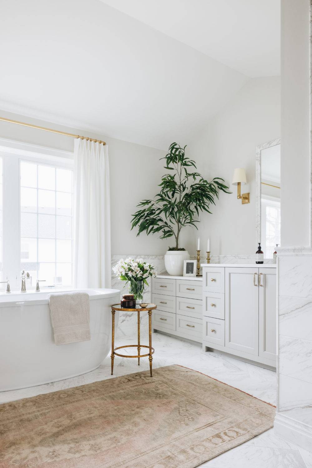 Large bathroom with white marble tile walls and floor and freestanding tub